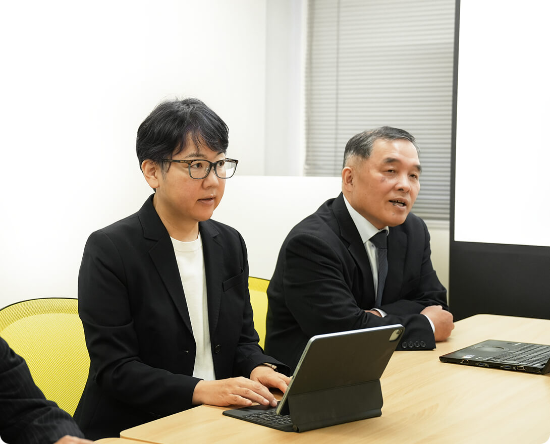パソコンの前に座って誰かと話をしている女性と男性の写真